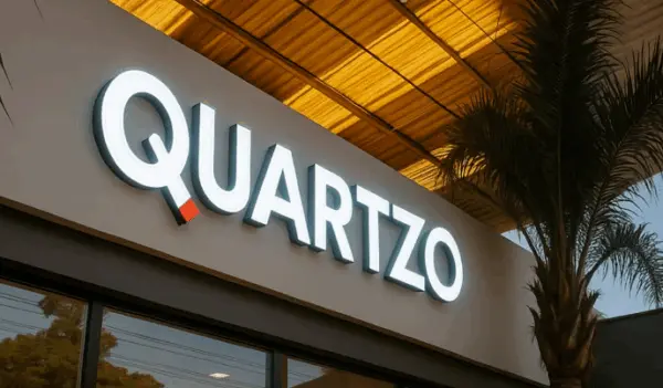 Letreiro em letras caixa iluminadas, instalado sob marquise, fotografado ao entardecer